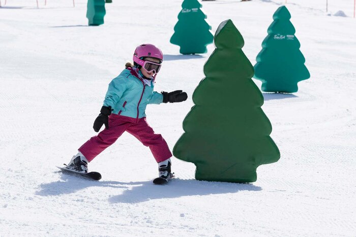 Child skis around an obstacle in the shape of a tree