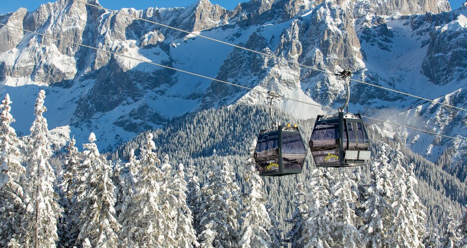 Two cabins of the Rittisberg combination lift with snowy mountains.