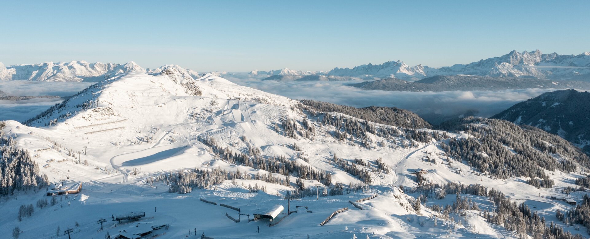 Shuttleberg ski area with lifts, slopes, snowy hills, forest and mountain panorama | © Shuttleberg