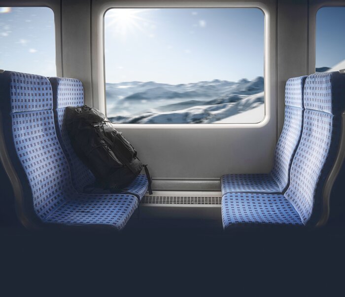 Four train seats and in the window you can see a snowy winter landscape