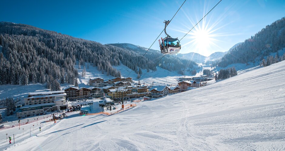 Cable car in Zauchensee valley with snowy slopes, powder snow and sun in background