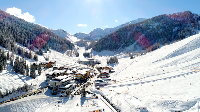 Zauchensee valley station with slopes, lifts, snowy mountains, skiers enjoying the sun