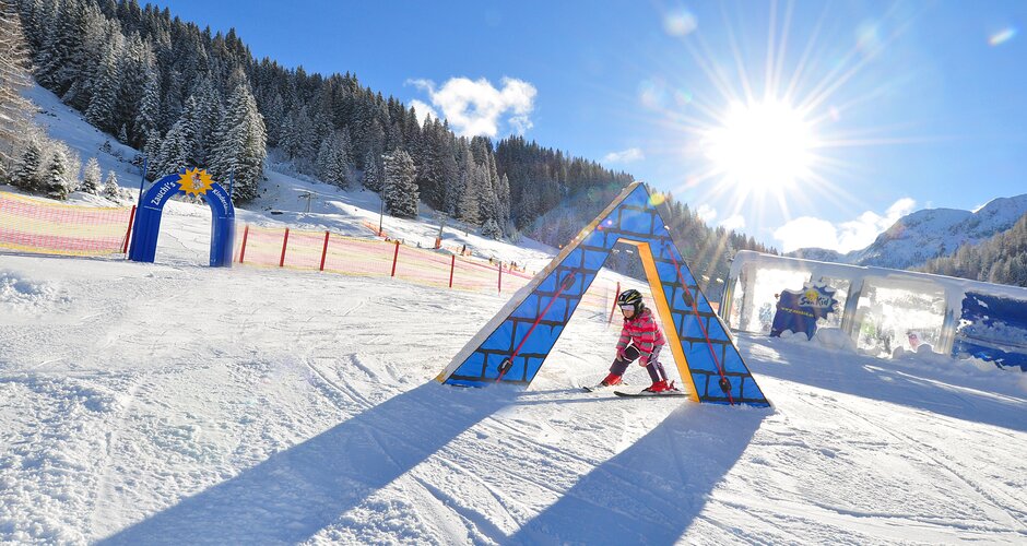Child on skis passing colourful obstacle in Kinderland Zauchensee in sunshine