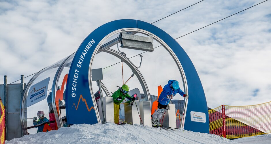 Two young skiers start simultaneously from Skimovie gate in Zauchensee