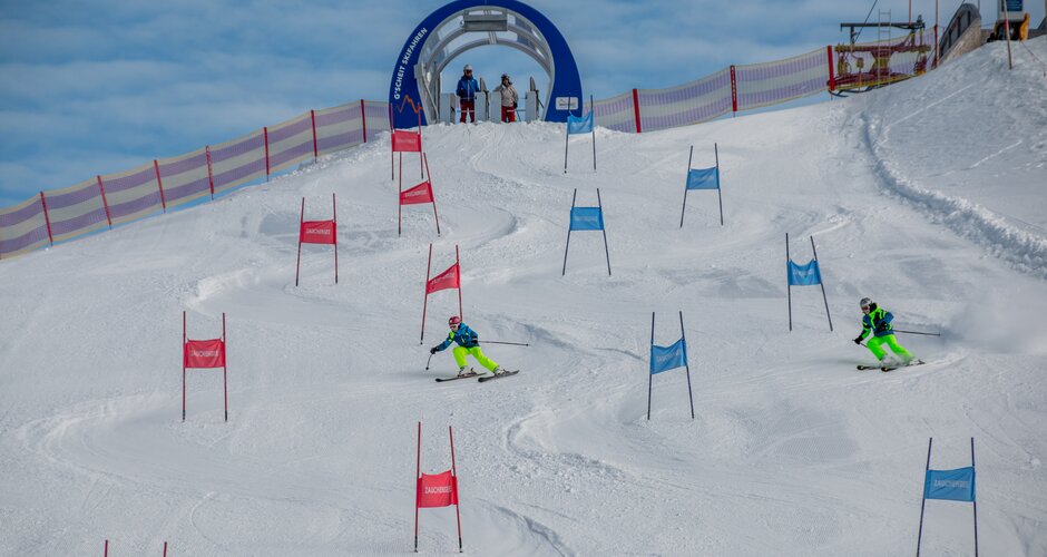 Two skiers in parallel slalom between red and blue gates in Zauchensee