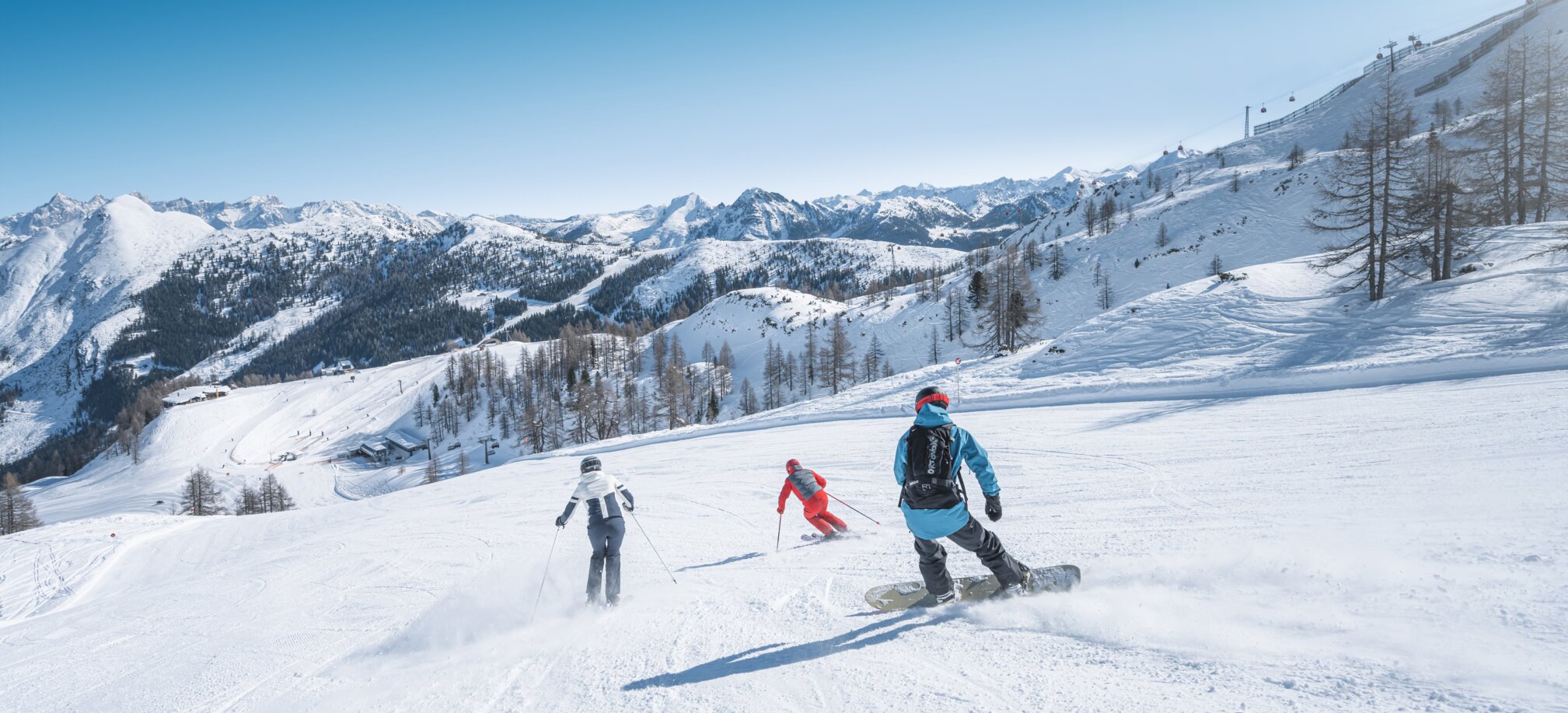 Three winter sports enthusiasts skiing and snowboarding together on the slope