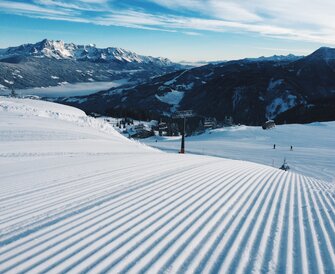 Freshly groomed ski slope with a chairlift and snowy mountains. | © Ski amadé