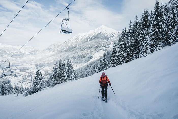 Skitourengeherin steigt am Graukogel unter Sessellift mit Talblick durch den Schnee | © Gasteinertal Tourismus GmbH, Christoph Oberschneider