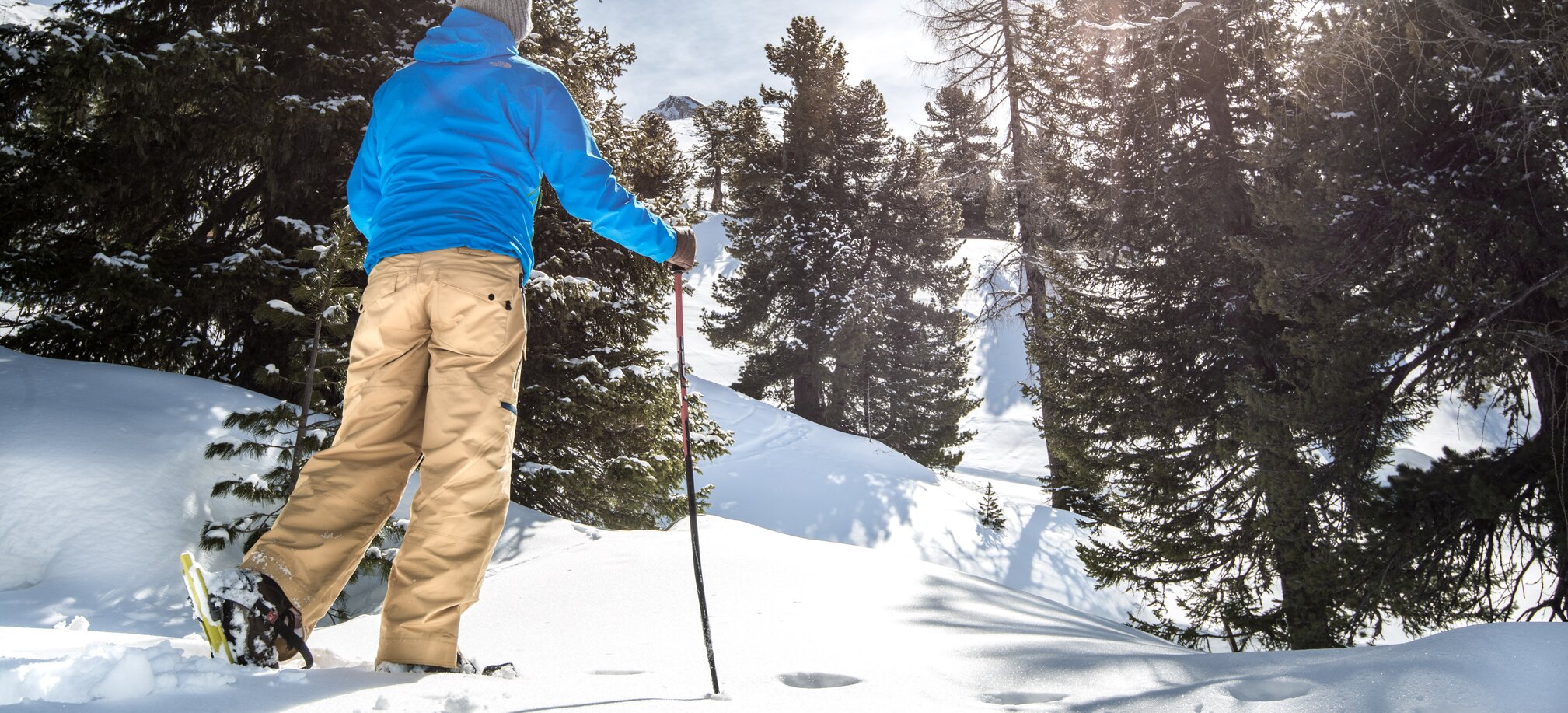 Person with snowshoes and pole in snowy forest area under sunshine in Gastein | © Gasteinertal Tourismus GmbH