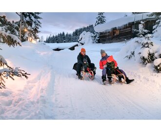 Parents and kids tobogganing together on winter holiday in Gastein | © GTG