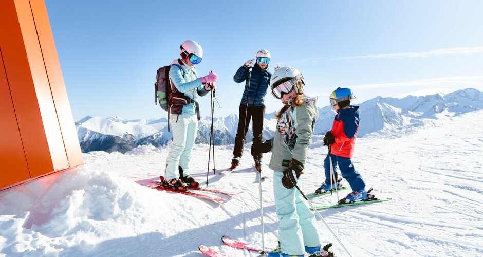 Two adults and two kids with skis on the summit in sunshine in Gastein | © Gasteinertal Tourismus GmbH, Manuel Marktl/Marktl Photography