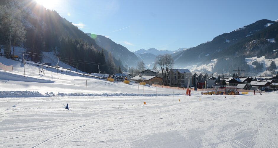 Wide family slope in Dorfgastein with practice lift and sunny winter scenery