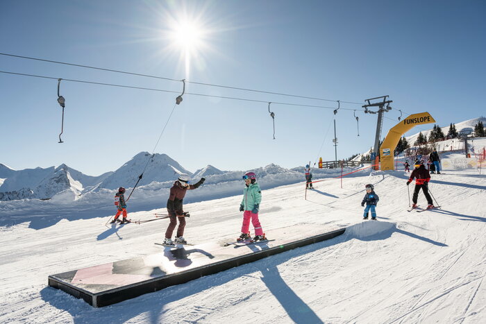 Kids and adults skiing in the sunny Funslope with wave course in Grossarltal ski area | © TVB Großarltal / Lorenz Masser
