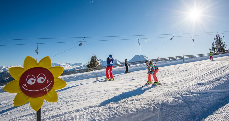 Happy child skiing down a practice slope in the sun during ski school in Grossarltal