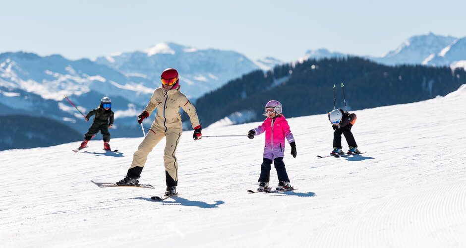 Adult skiing with three kids on wide sunny slope in the Alps | © Hochkönig Tourismus GmbH
