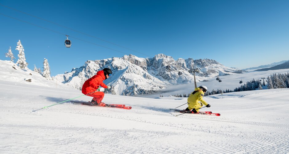 Two skiers on freshly groomed slope with view of the snowy Hochkönig mountain range | © Hochkönig Tourismus GmbH