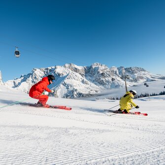 Two skiers on freshly groomed slope with view of the snowy Hochkönig mountain range | © Hochkönig Tourismus GmbH