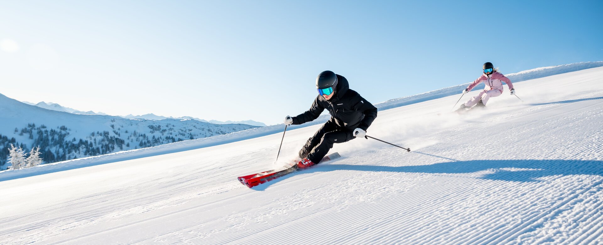 Two skiers on freshly groomed slope in sunshine in Maria Alm at Hochkönig | © Hochkönig Tourismus GmbH