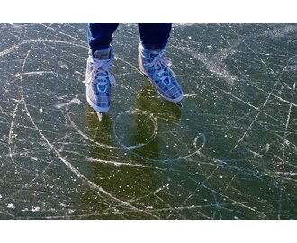 Close-up of ice skates on scratched surface of a frozen natural lake | © Pixabay