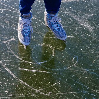 Close-up of ice skates on scratched surface of a frozen natural lake | © Pixabay